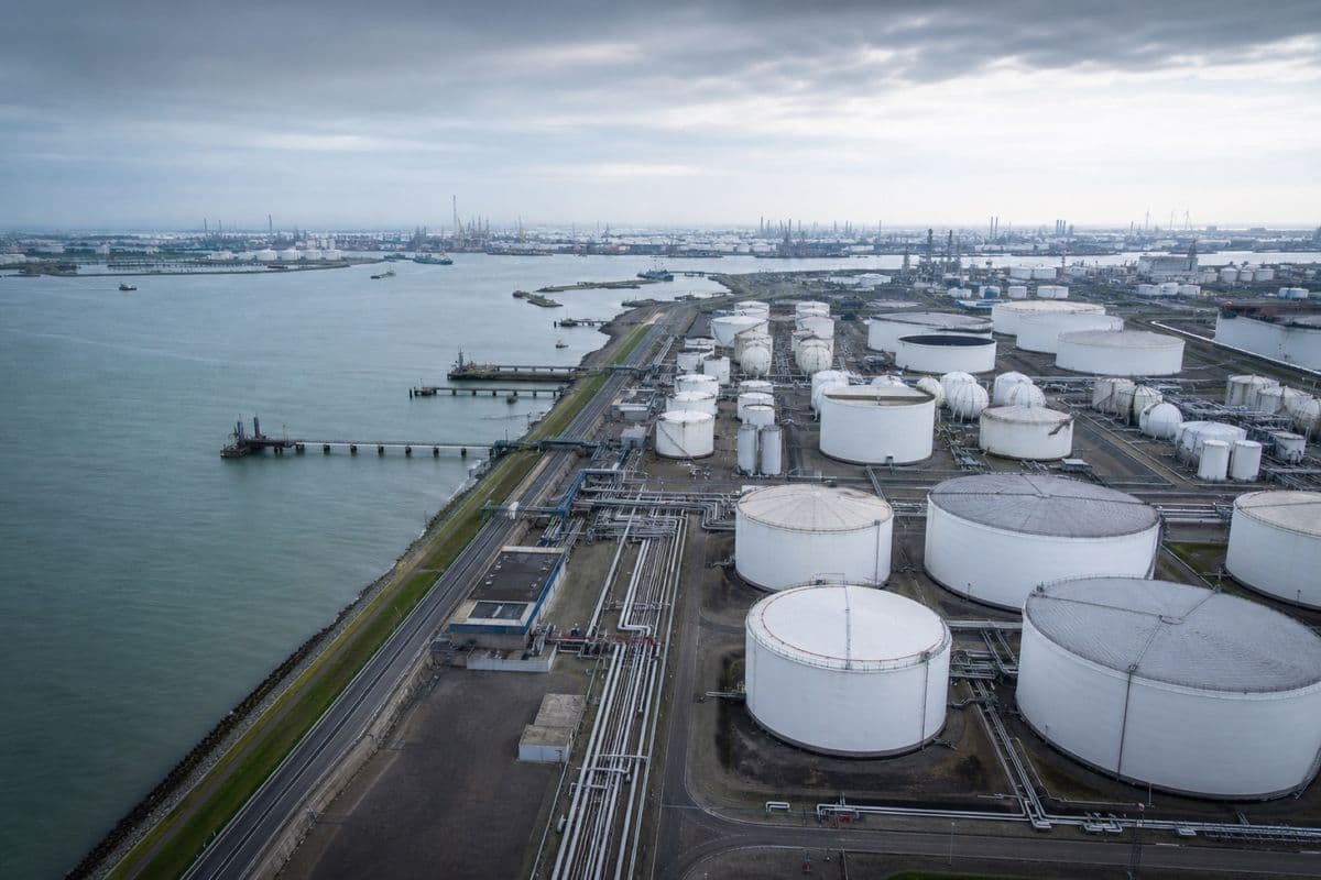 Tank storage terminal at dusk — rows of bulk-liquid storage tanks against a dark sky